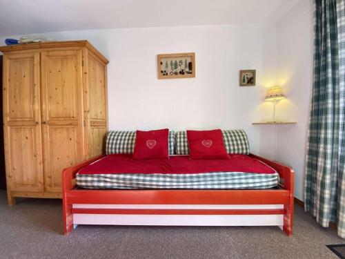 a red couch with red pillows in a room at Appartement Praz-sur-Arly, 2 pièces, 4 personnes - FR-1-603-60 in Praz-sur-Arly