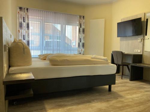 a bedroom with a bed and a desk and a television at Landhotel Vosse-Schepers in Rhede