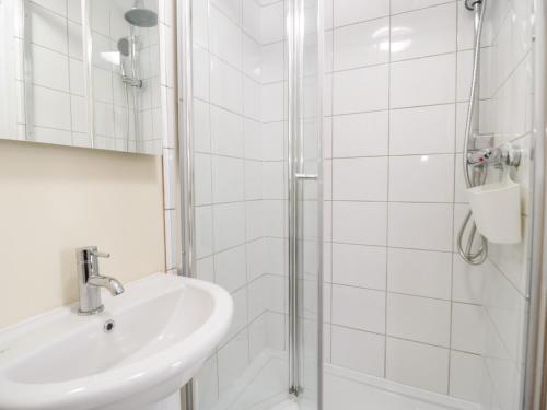 a white bathroom with a sink and a shower at Bryn Dedwydd Cottage in Betws-y-coed