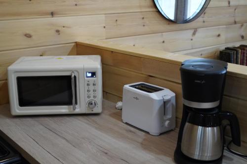 - un four micro-ondes assis sur un comptoir à côté d'une cafetière dans l'établissement cottage scandinave 92, à Bourbourg