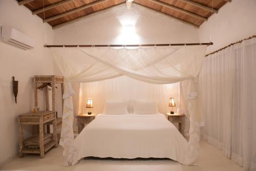 a bedroom with a white bed with a canopy at Maion Hotel e Boutique in Praia do Espelho