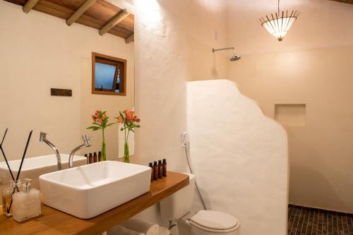 ein Badezimmer mit einem weißen Waschbecken und einem WC in der Unterkunft Maion Hotel e Boutique in Praia do Espelho