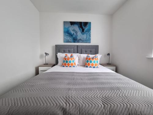 a bedroom with a large bed with orange pillows at Beautiful 4 bed home, Sleeps 8, driveway parking, With sky & BT sports in Manchester