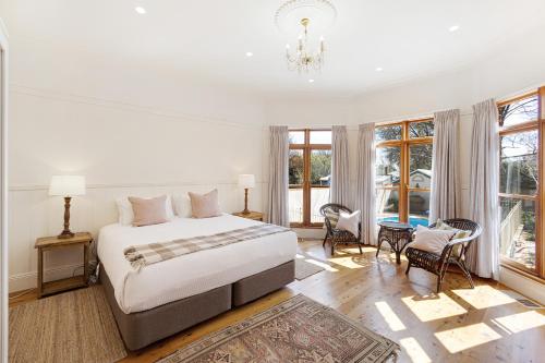 a white bedroom with a bed and some windows at Mia Mia Mudgee in Mudgee