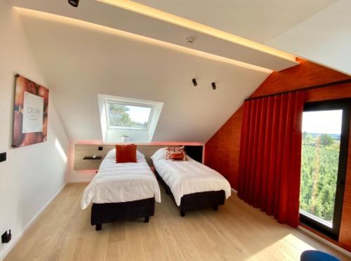 Le Clos du Verger في آوبيل: سريرين في غرفة نوم مع ستائر حمراء