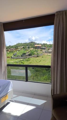 a room with a window with a view of a field at - Belezas do Monte Chalé e Suíte- La na Roça in Monte das Gameleiras