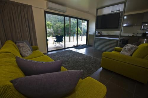 a living room with a yellow couch and a television at Tyenna River Cottages in Tyenna