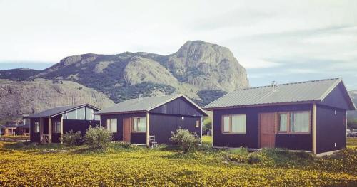 trzy domy na polu z górami w tle w obiekcie El Relincho w mieście El Chaltén