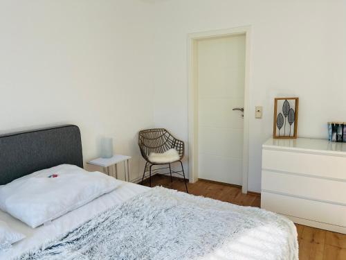 a white bedroom with a bed and a chair at Connect 9.3 in Dorum-Neufeld