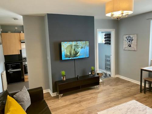 a living room with a couch and a tv on a wall at Pendle House - Apartment 3 in Colwyn Bay