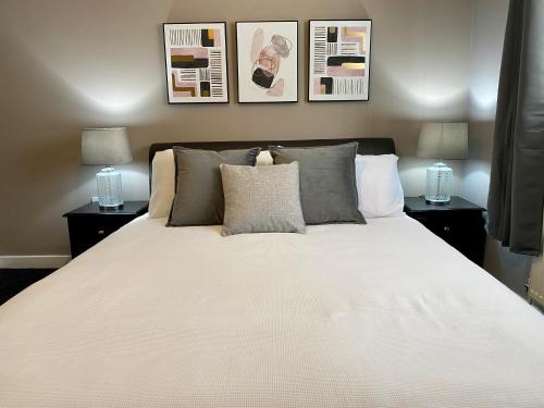 um quarto com uma grande cama branca e 2 candeeiros em Pendle House - Apartment 3 em Colwyn Bay