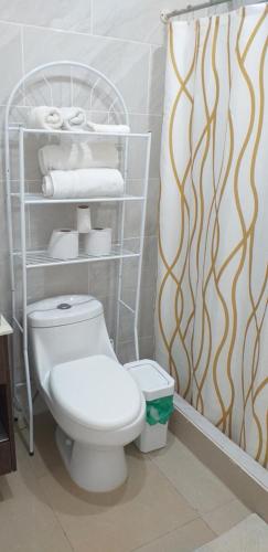 a bathroom with a toilet and a shelf with towels at Pura Vida Condo in Tamarindo