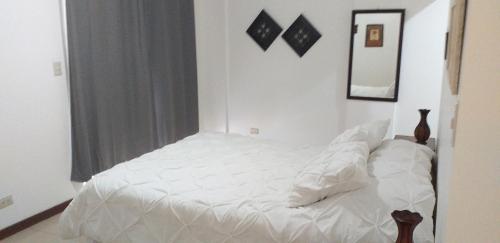 a white bed in a room with a window at Pura Vida Condo in Tamarindo