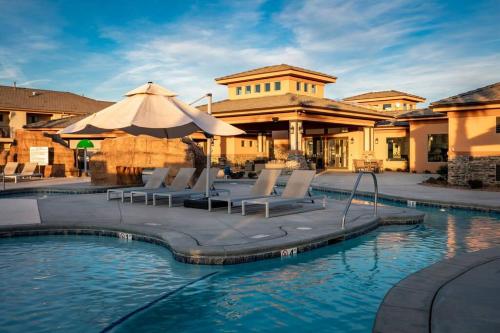 a pool with chairs and an umbrella in front of a building at Discover Zion Mountain, Private Hot Tub-3 Bedroom in Hurricane