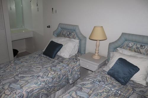 a bedroom with two beds with pillows and a lamp at Little Reef Villa in Saint James