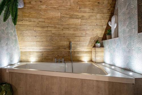 a bath tub in a bathroom with a wooden wall at Style & opulence in Georgian chapel w Parking in Bath