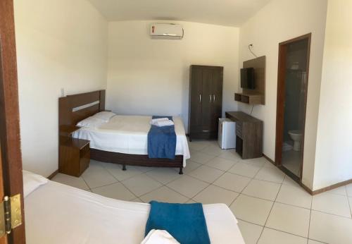 a hotel room with two beds and a television at Pousada Alto do Sossego in Rio de Contas