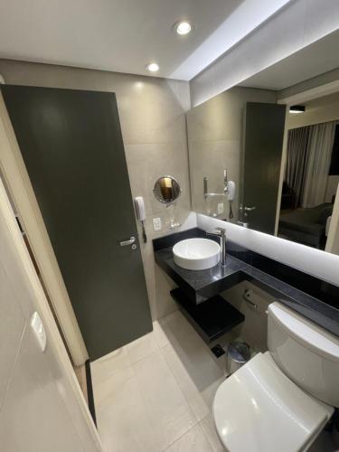a bathroom with a toilet and a sink and a mirror at Flat particular incrível dentro do hotel M Ibirapuera em Moema in Sao Paulo