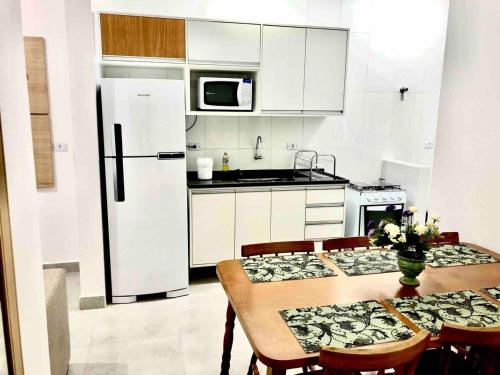 a kitchen with a table with chairs and a refrigerator at Rafael Apartamentos 800m da Praia da Maranduba in Ubatuba