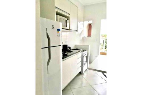 a white kitchen with a refrigerator and a sink at Rafael Apartamentos 800m da Praia da Maranduba in Ubatuba