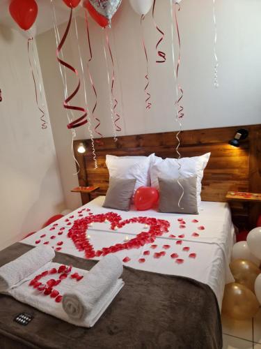 ein Bett mit einem Herz aus Rosen und Ballons in der Unterkunft T2 Jacuzzis et piscine au centre ville de Port-Louis in Port-Louis