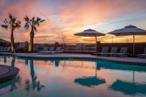 a pool with chairs and umbrellas at sunset at Discover Zion Mountain, Private Hot Tub-3 Bedroom in Hurricane