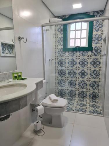 a bathroom with a toilet and a sink and a window at Pousada Candelabro in Tiradentes