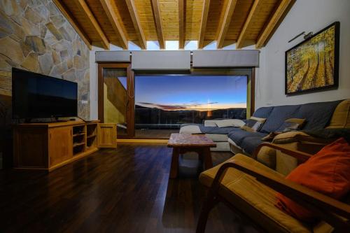 uma sala de estar com um sofá e uma televisão de ecrã plano em La Portilla de Gredos. Casa rural em Hoyos del Espino