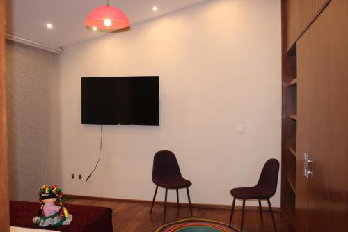 a living room with two chairs and a television on a wall at Casa Luna Coyoacan in Mexico City