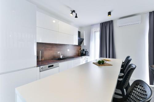 a white kitchen with white cabinets and black chairs at Jean-Marie in Zaton