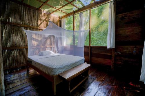 ein kleines Bett in einem Zimmer mit Fenster in der Unterkunft Amak Iquitos Ecolodge - All Inclusive in Santa Clara