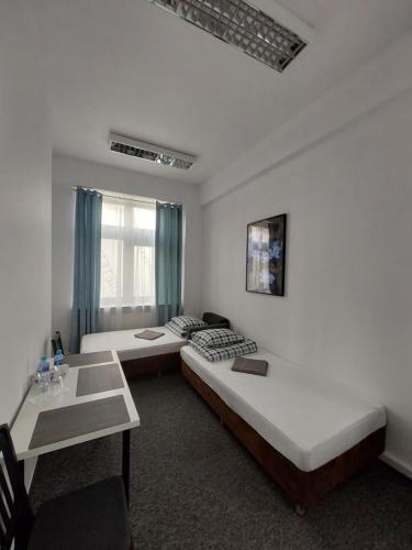 Pokój z 2 łóżkami, stołem i biurkiem w obiekcie Pinto Guest Rooms w Warszawie