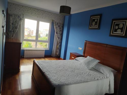a blue bedroom with a bed and a window at Piso in Boiro