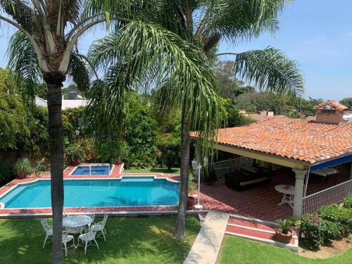 a house with a swimming pool and palm trees at Relax and Enjoy Cuernavaca Pet Friendly in Cuernavaca