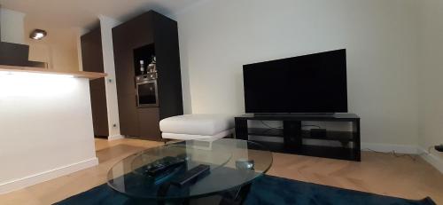 uma sala de estar com uma mesa de vidro e uma televisão em Allées historiques du Parc de la Colombière, appt haut de gamme em Dijon