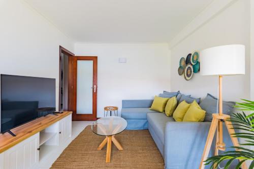 a living room with a blue couch and a flat screen tv at Mira-Ria - Apartamento em bairro calmo e central in Aveiro