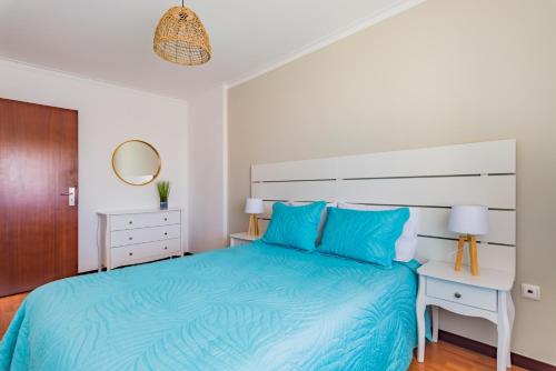 a white bedroom with a blue bed and a table at Mira-Ria - Apartamento em bairro calmo e central in Aveiro