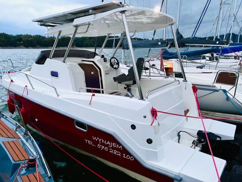 a red and white boat is docked in the water at VIP JACHT in Polańczyk