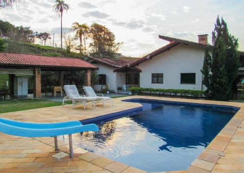 una piscina con 2 sillas y una casa en Lindo Sitio na beira da represa em Santa Isabel - SP, en Igaratá