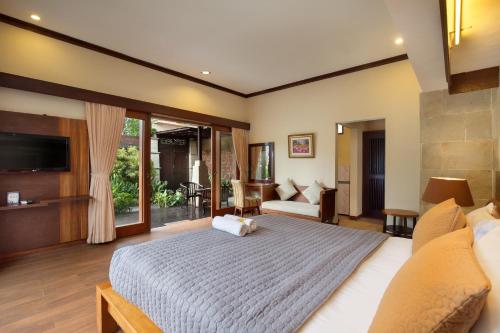 クタにあるMahe Garden Inn and Villas by Kamaraのベッドルーム(大型ベッド1台付)、リビングルームが備わります。