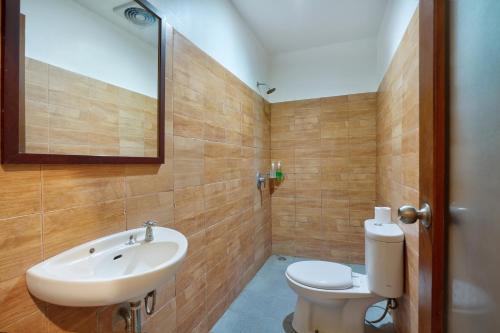 ein Badezimmer mit einem Waschbecken, einem WC und einem Spiegel in der Unterkunft Mahe Garden Inn and Villas by Kamara in Kuta