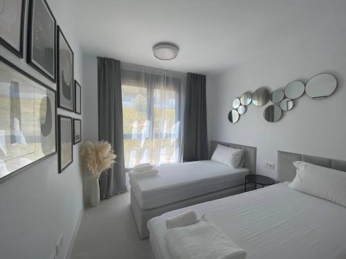 een witte kamer met 2 bedden en een raam bij Estepona Luxury Apartment in Estepona