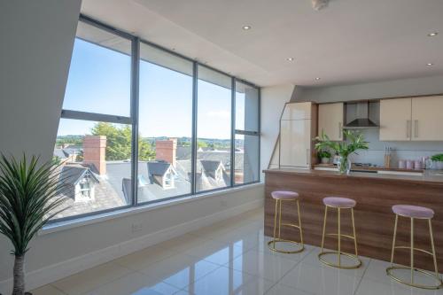a kitchen with a large window and stools at Rooftop Apartment At Queens Beautiful views in Belfast