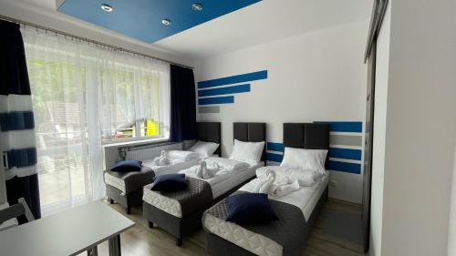 Cette chambre comprend deux lits, un canapé et une table. dans l'établissement Willa Barwy Wspomnień, à Muszyna