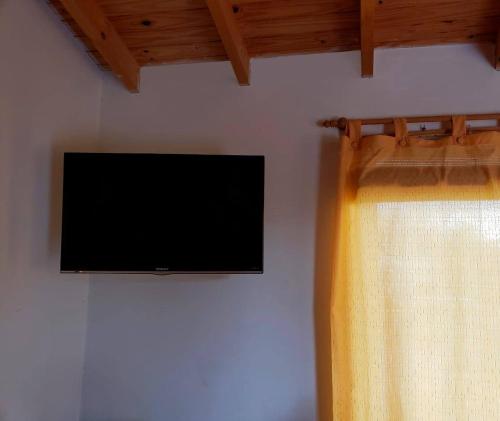 TV de pantalla plana en la pared con cortina en Cabañas Las Nanys en Balneario Claromecó