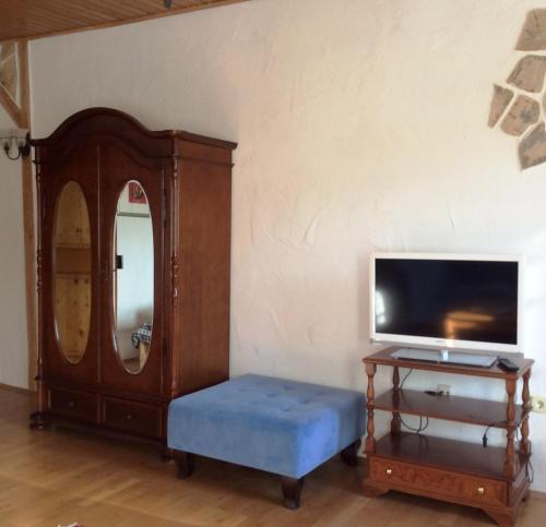 a room with a mirror and a tv and a blue stool at Ferienwohnung Rosenlehner in Kiefersfelden