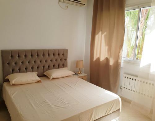 a bedroom with a large bed with a large window at Maison plain-pied avec piscine chauffée in Tunis