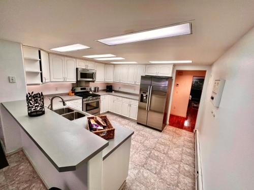 a kitchen with white cabinets and a stainless steel refrigerator at Newly Remodeled spacious units, minutes from mountains, inlet, downtown and airport in Anchorage