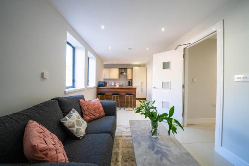 a living room with a blue couch and a kitchen at BOTANIC APARTMENT SLEEPS 6 in Belfast