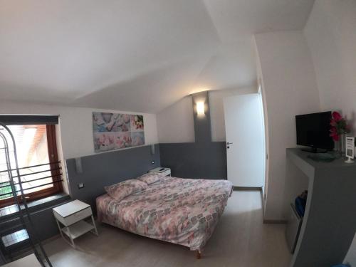 een kleine slaapkamer met een bed en een televisie bij Bella Vita Guesthouse -parcheggio privato interno in Arona